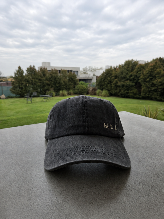 Gorra MEKap Vintage Prelavada en negro, de frente, con el wordmark MEK bordado en hilo dorado