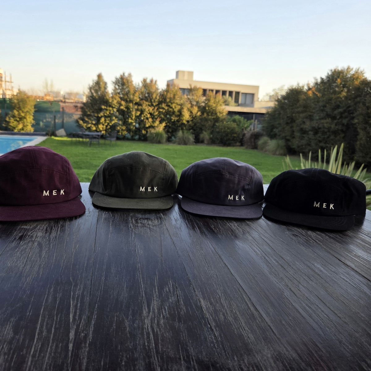 Las cuatro gorras MEKap Five Panel en fila: bordó, verde, gris y negra